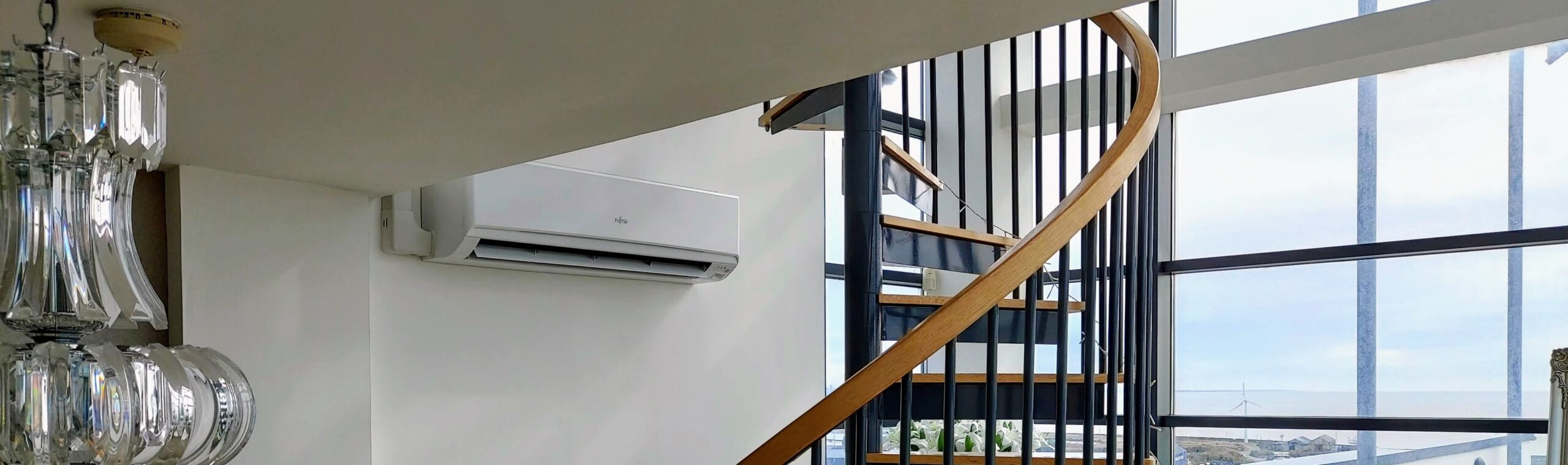 Residential wall mounted air conditioning installation of wall mounted system unit next to spiral staircase, representing our installation, highlighting our services in Swansea and Gloucester